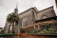 阴天里，一对夫妇手拉手走过一座历史悠久的石砌教堂，浪漫与文化气息油然而生