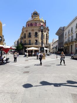 Lively street scene in Jerez de la Frontera, featuring a historic plaza under a clear blue sky.
