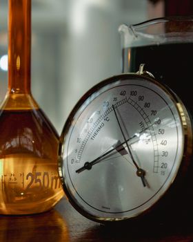 Detailed view of laboratory glassware and thermometer on a wooden surface.