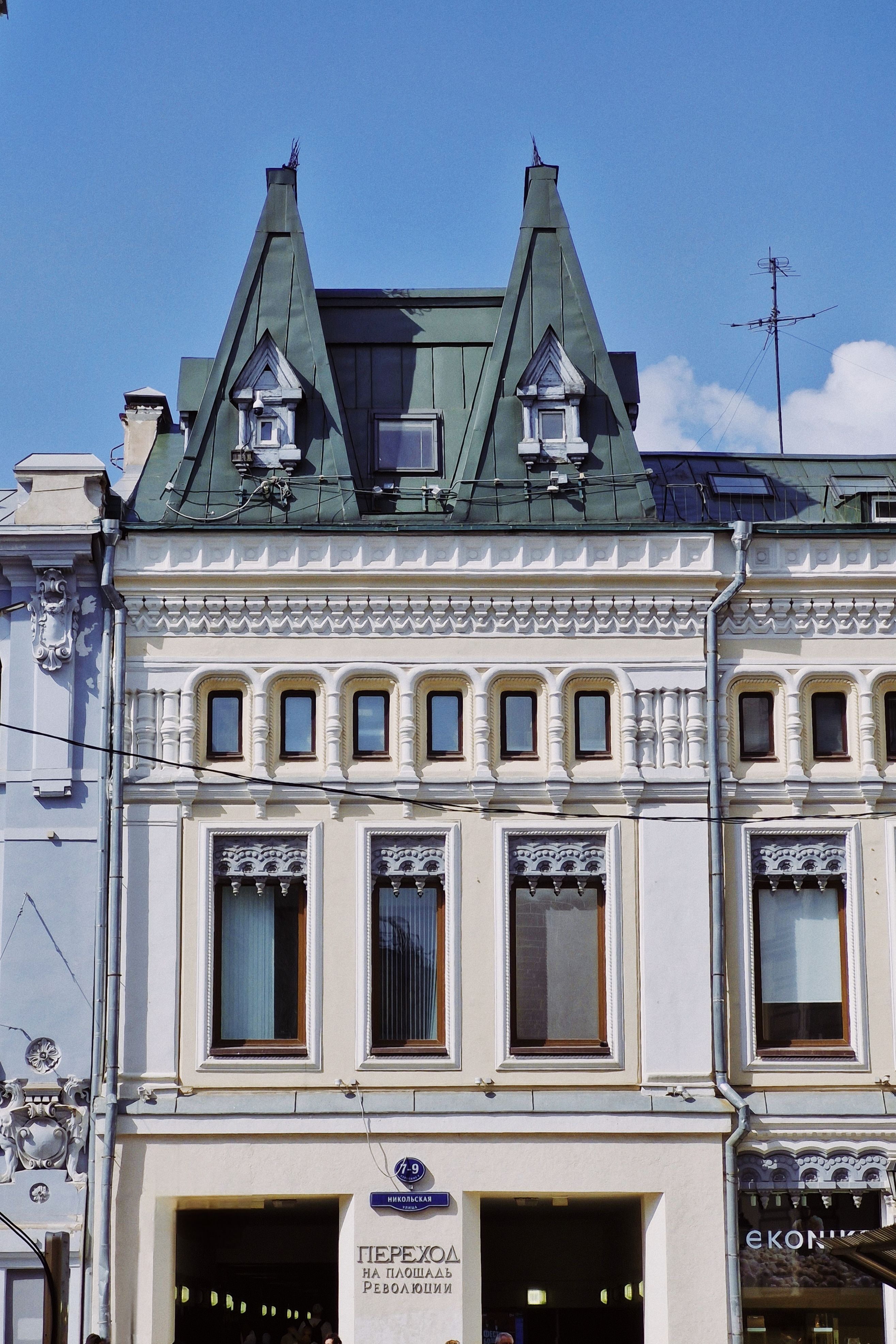 Elegant European building facade with Gothic-inspired roof peaks under a clear blue sky.