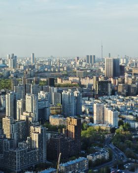 Wide aerial view of a modern city with dense buildings under a clear sky.