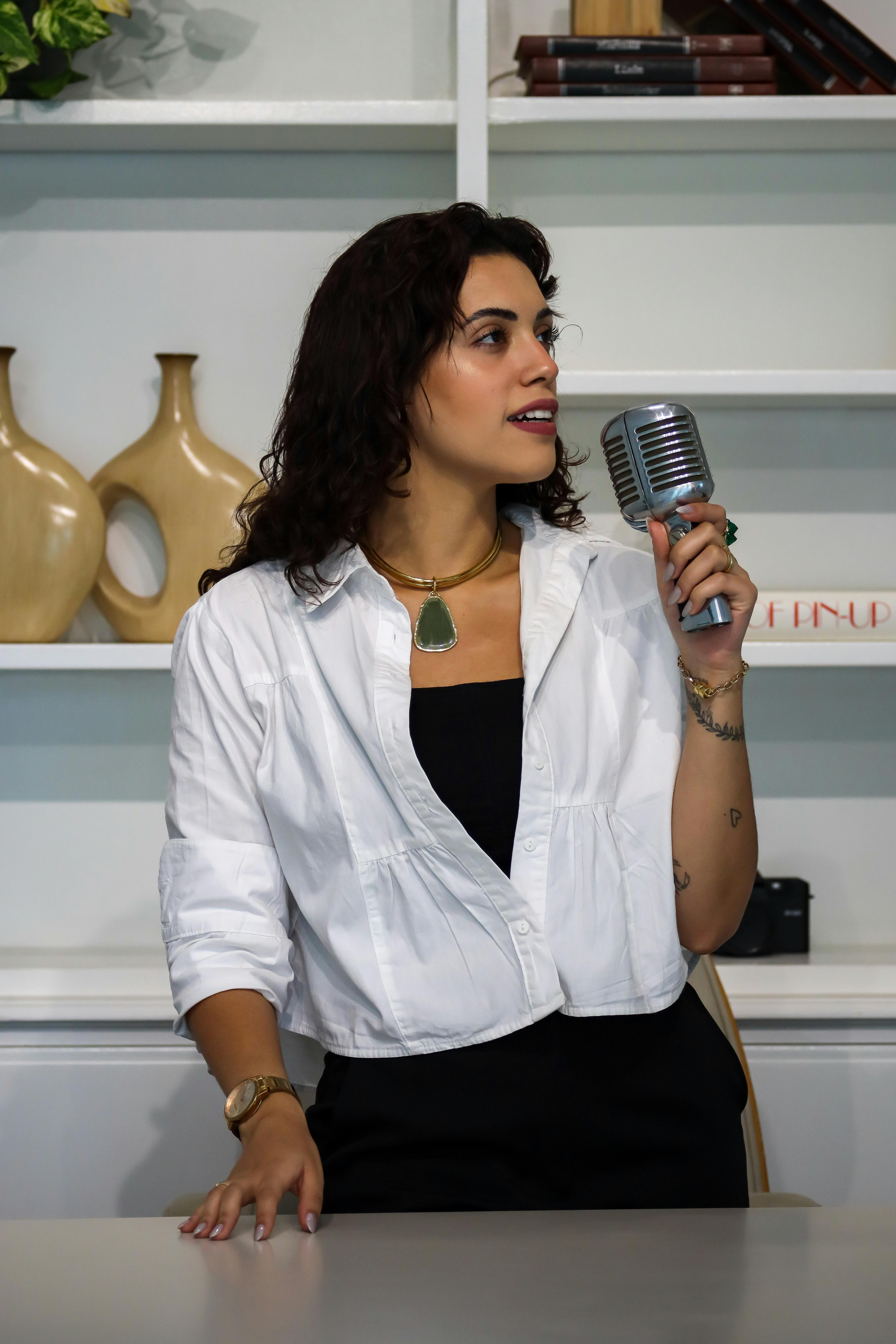 Free Elegant woman holding a retro microphone indoors, exuding confidence. Stock Photo