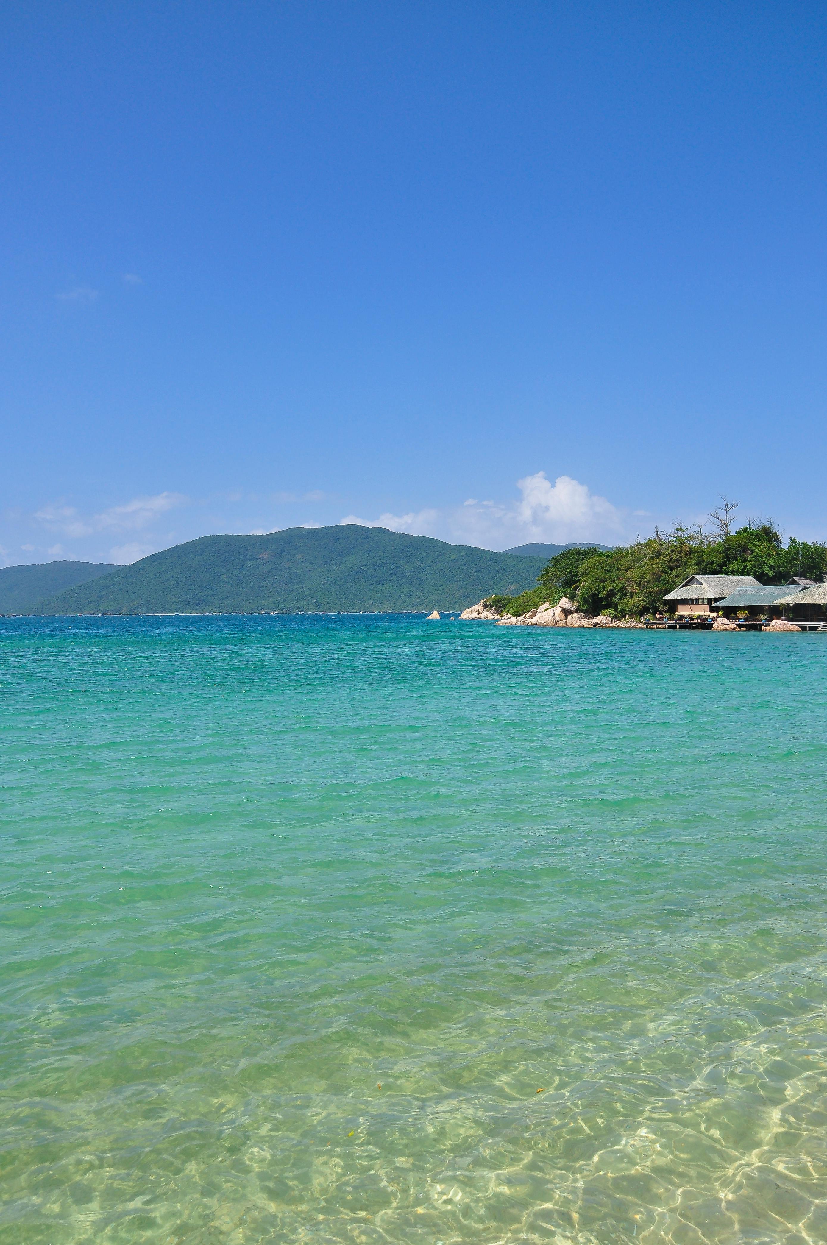 Discover the serene beauty of a pristine beach in Khánh Hòa, Vietnam, with turquoise waters and a vibrant blue sky.