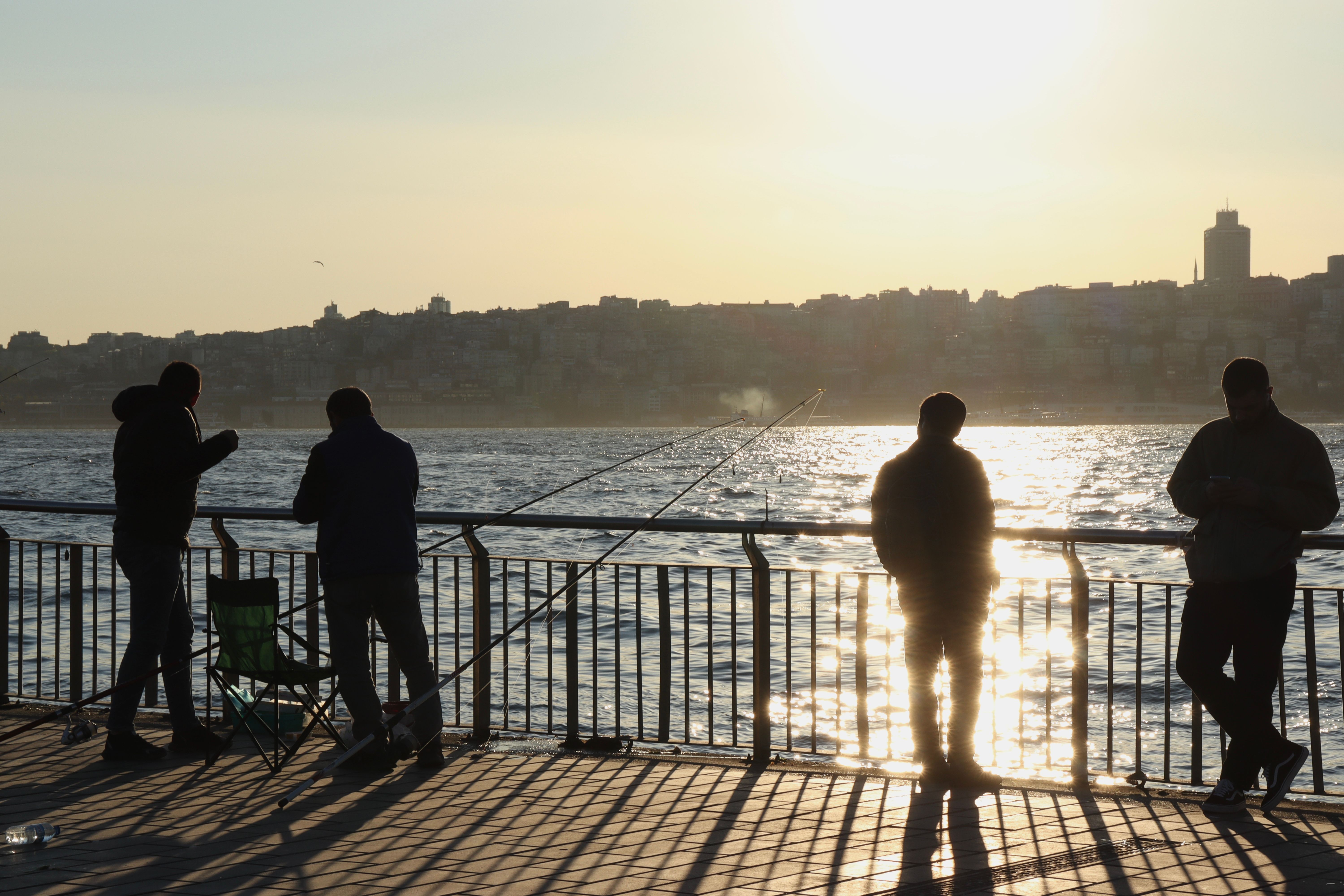 Silhouette of Fishermen at Sunset by the Sea · Free Stock Photo