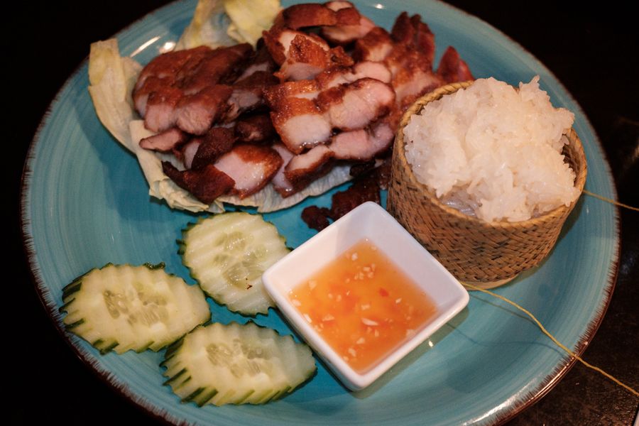 Grilled Thai pork served with sticky rice in a woven basket and a chile-lime dipping sauce