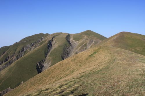 Free Beautiful rolling mountains with green and brown hues under a clear blue sky, capturing the essence of nature's tranquility. Stock Photo