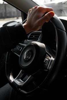A detailed view of a hand gripping a car's steering wheel, capturing driving essence.