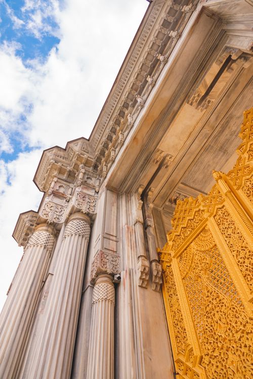 Free Close-up of an ornate historical building facade with a detailed golden gate and decorative stone carvings. Stock Photo