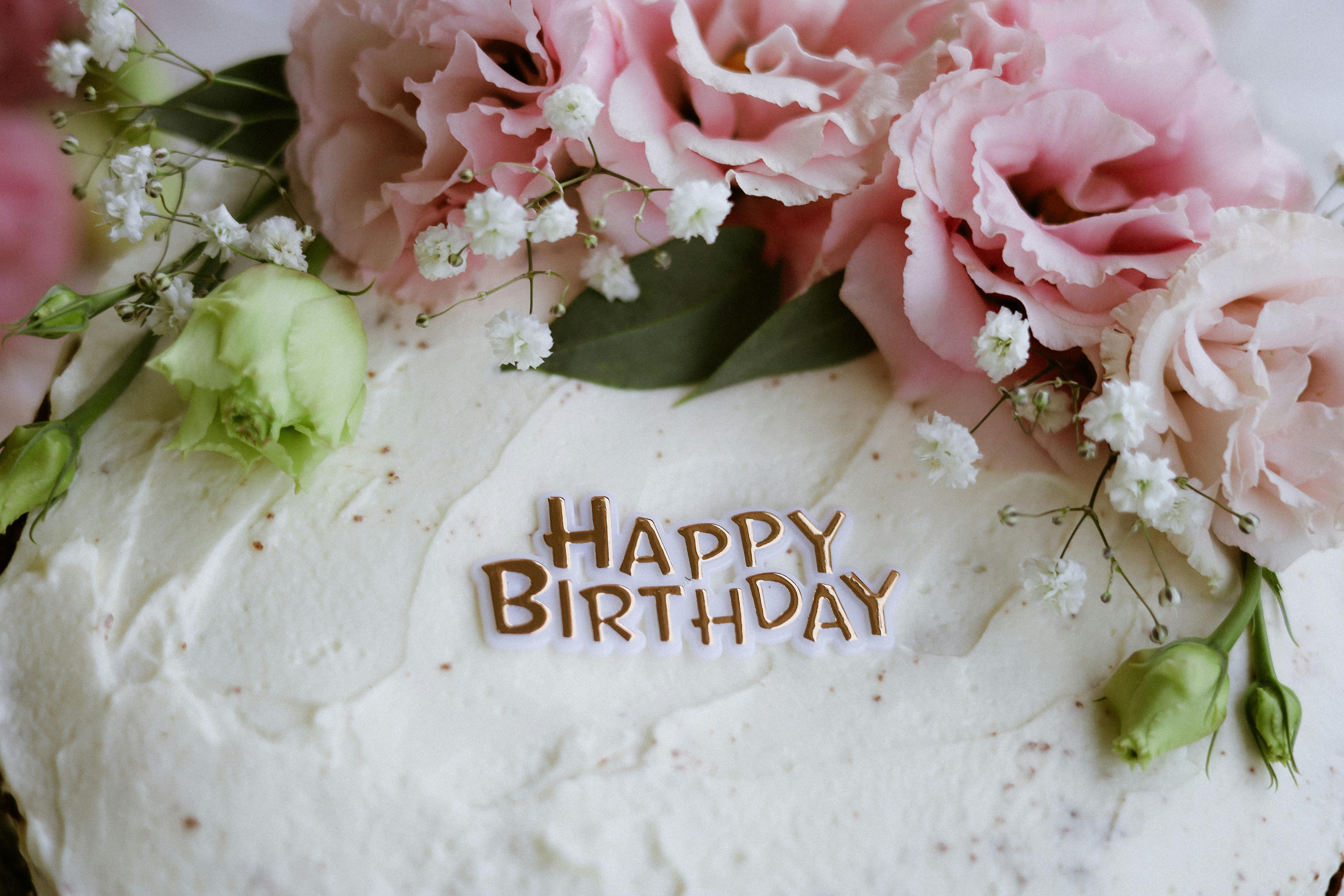 Close-up of a birthday cake decorated with pink flowers and 'Happy Birthday' text.