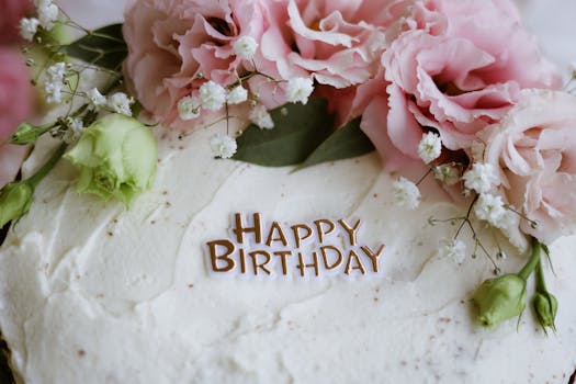 Close-up of a birthday cake decorated with pink flowers and 'Happy Birthday' text.