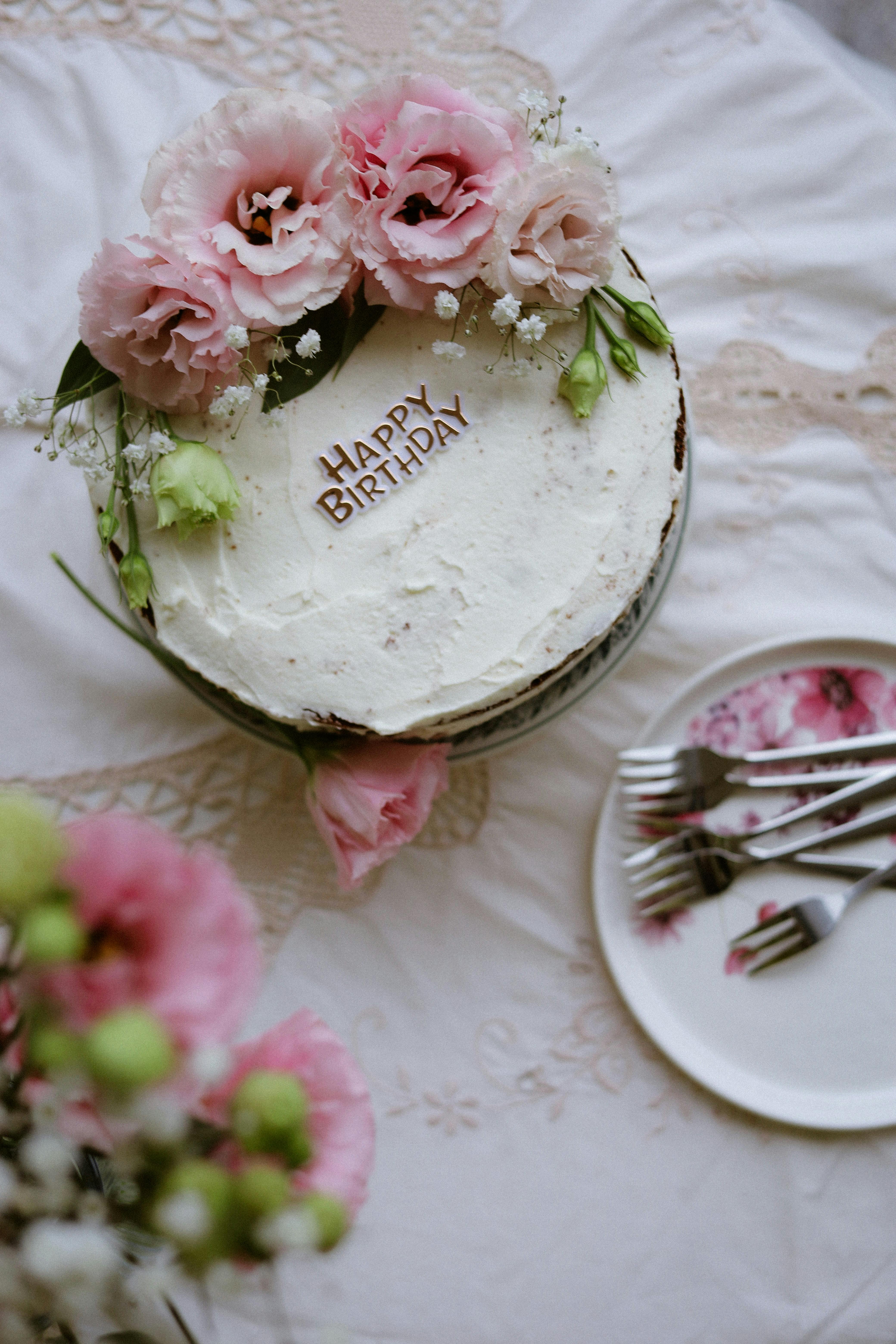 A beautifully decorated birthday cake with pink flowers and 'Happy Birthday' written on top.