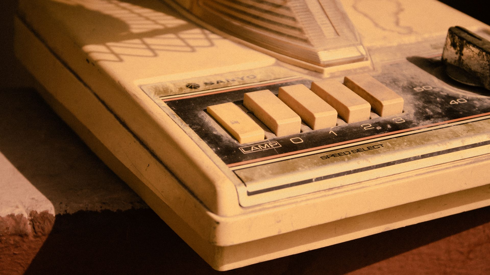 Close-up of a vintage Sanyo speed selector and buttons with a retro aesthetic and warm tones.