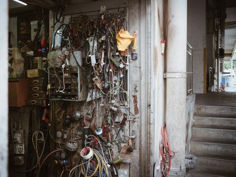 Wires, tools, and gadgets clutter the wall of a mechanic's workshop showcasing an industrial vibe.