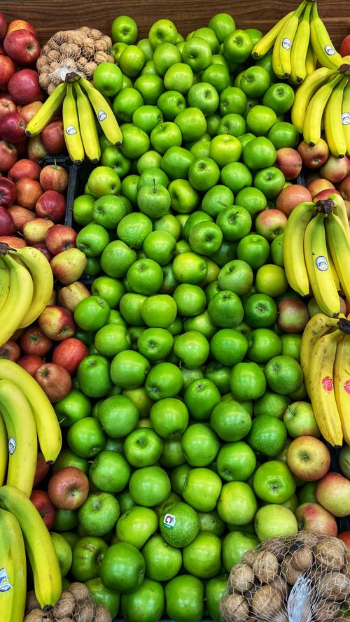 Free Vibrant display of green apples and bananas at a local market, perfect for healthy eating. Stock Photo