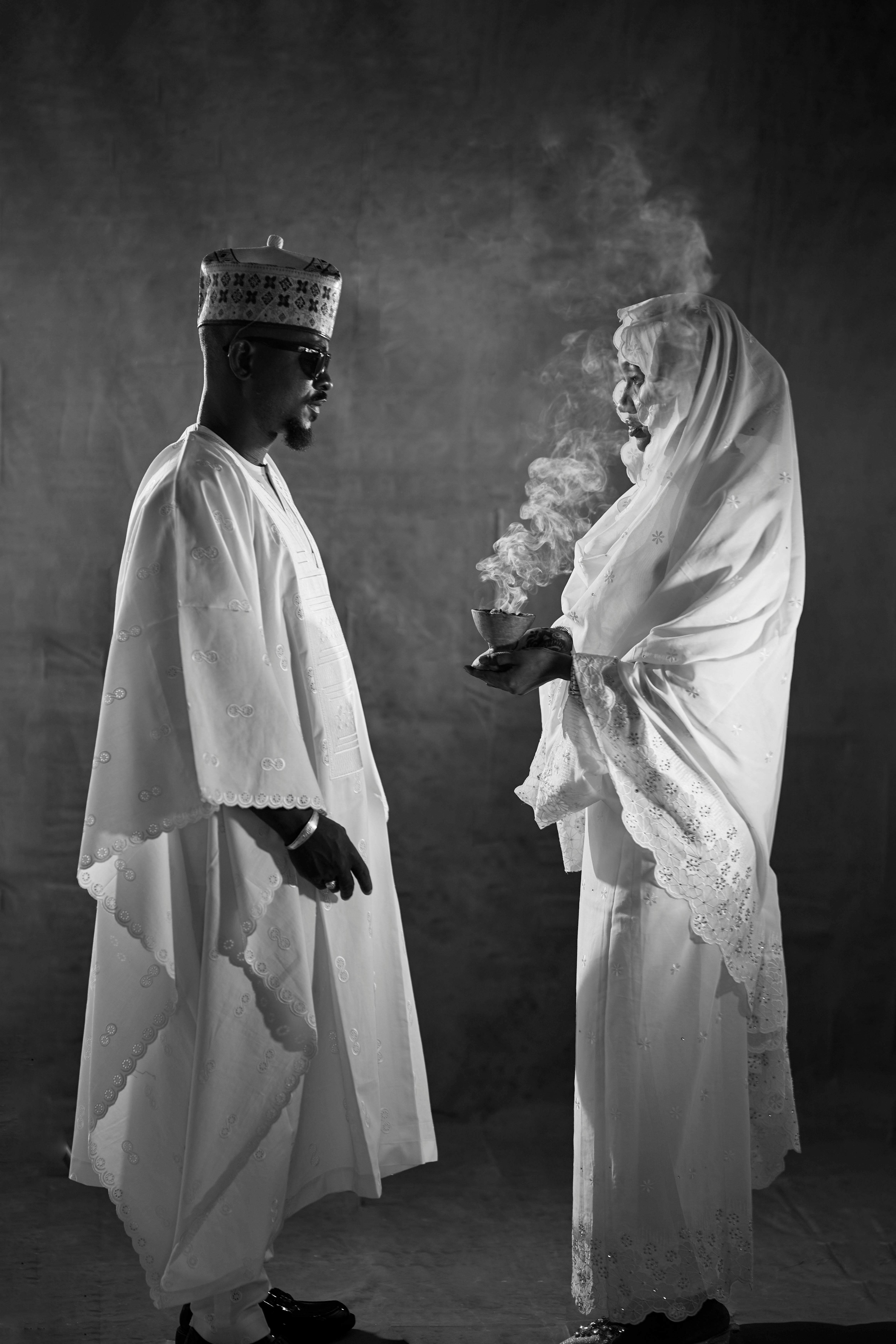 Two figures in white garments with incense smoke rising between them