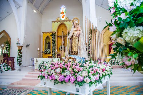 教会の祭壇の近くの花に囲まれた母と子の像