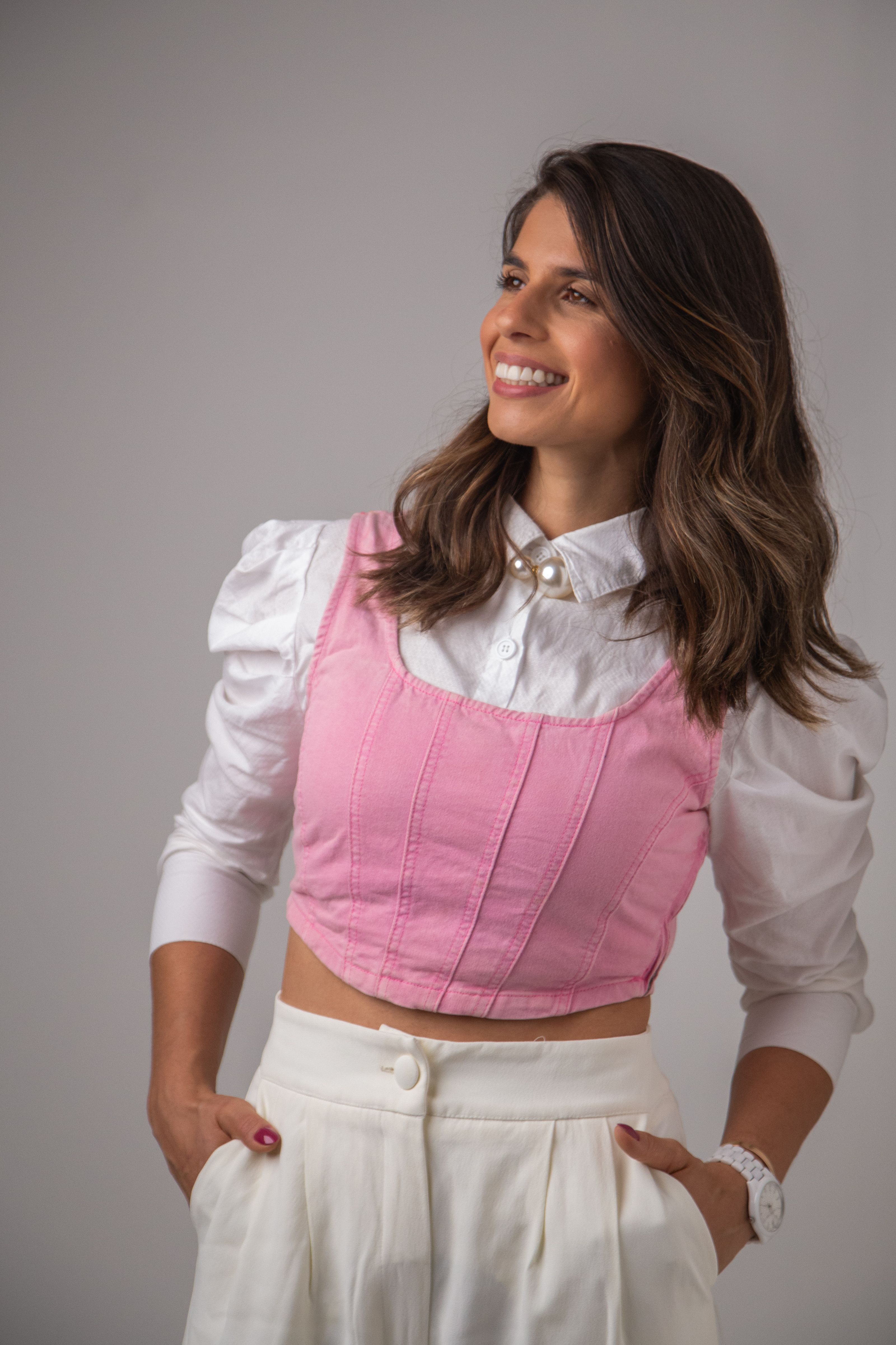 Uma mulher confiante em um traje elegante rosa e branco, exalando uma vibração alegre.