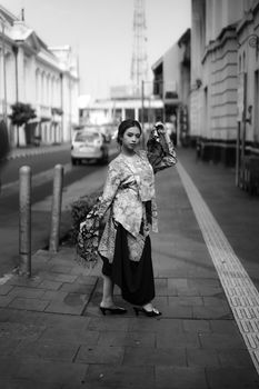 Black and white portrait of a woman in traditional dress posing on a city street. - Fotografer Sidoarjo