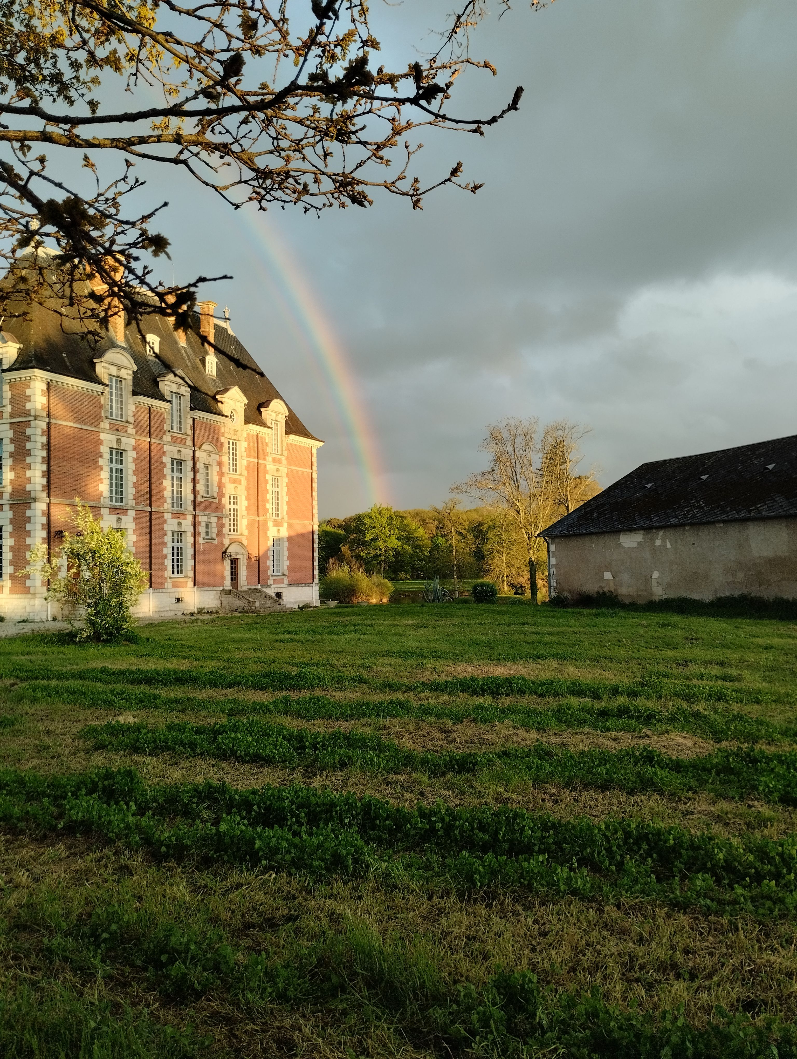 A scenic view of a countryside estate with a rainbow in the sky.