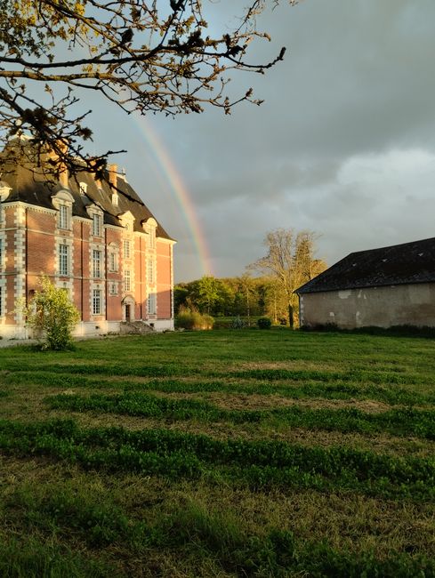 A scenic view of a countryside estate with a rainbow in the sky.