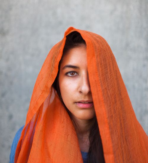 Free A captivating portrait of a woman wearing an orange scarf, highlighting diverse cultural fashion. Stock Photo