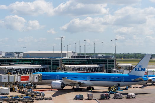 A KLM airplane is parked at an airport terminal under a sunny sky, ready for boarding.