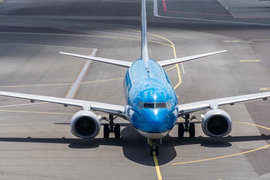A blue commercial airplane taxiing on an airport runway, ready for takeoff.