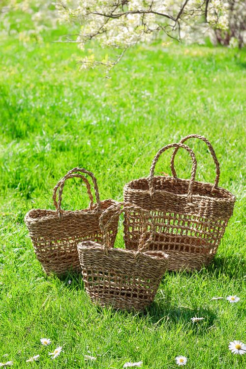 Free Three rustic woven baskets displayed outdoors on a lush green lawn during spring season. Stock Photo
