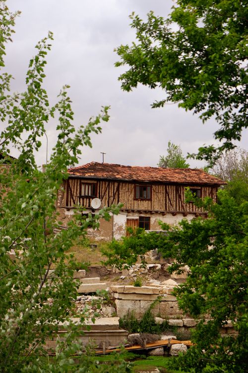 Free Charming rustic stone house surrounded by lush greenery and trees in a countryside setting. Stock Photo