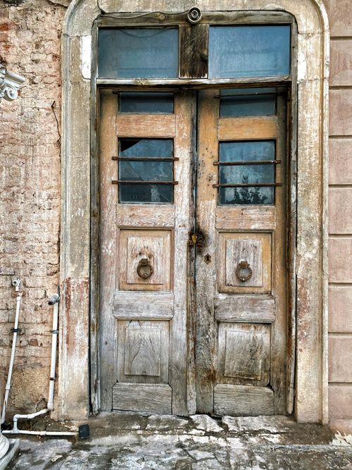 Free Aged wooden double doors with a rustic look and peeling paint in an old brick wall setting. Stock Photo