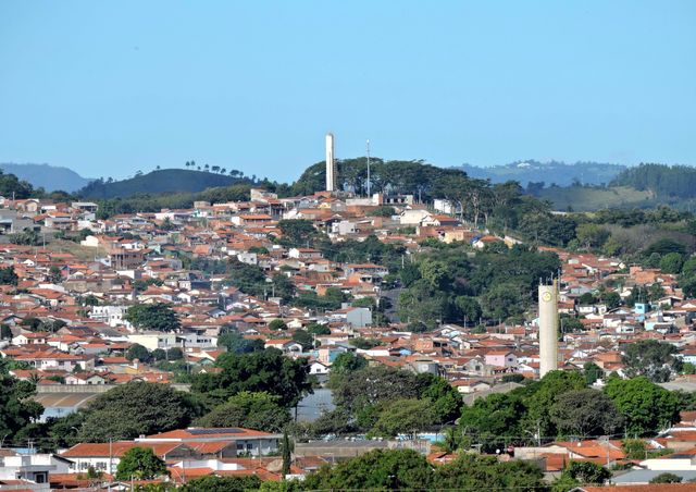 Charming aerial shot of a Brazilian town with lush greenery and red rooftops under a clear blue sky.