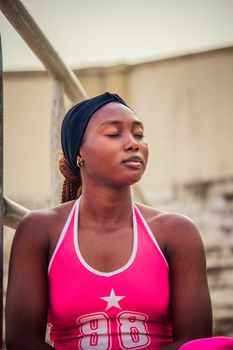 A serene woman in vibrant pink sportswear meditates outdoors, conveying calm and focus.