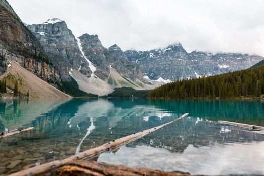 Tranquil Moraine Lake with Rocky Mountains reflecting under a cloudy sky in Banff National Park.