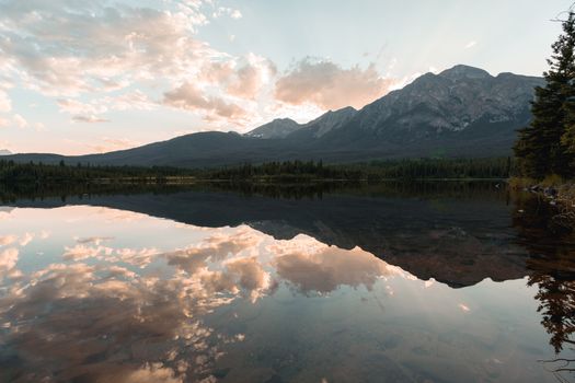 Breathtaking sunset over a serene lake in Jasper National Park, Canada, reflecting the rugged Rockies.
