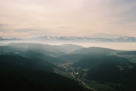 A serene view of the majestic Swiss Alps with morning mist over lush valleys.