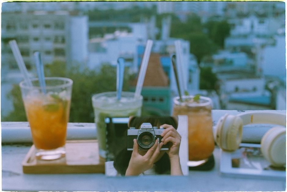 A vintage camera captures a vibrant rooftop cafe with colorful drinks and soft background blur.