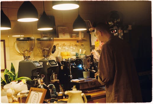 A barista making coffee in a warm, dimly lit cafe with industrial fixtures.
