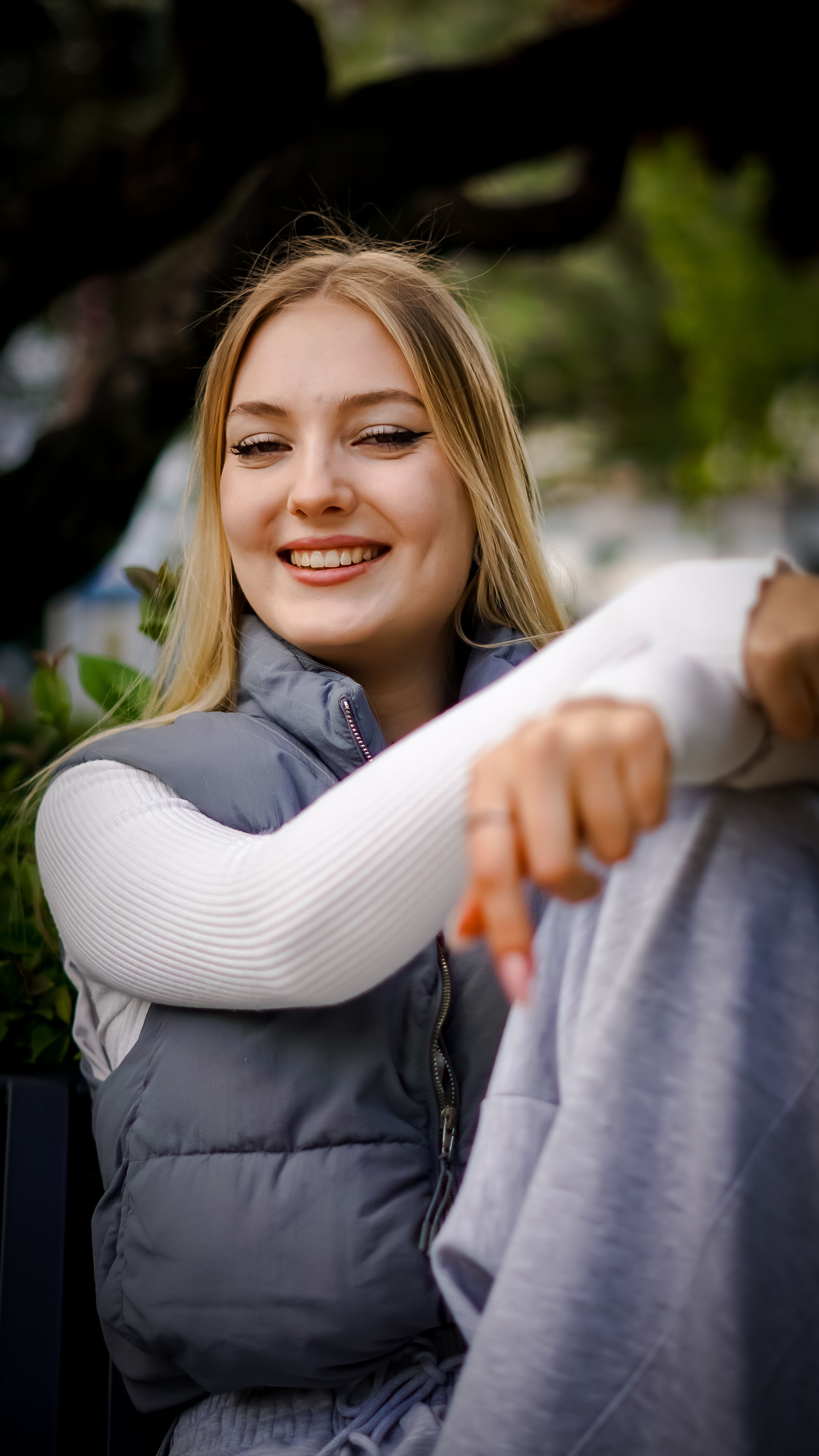 Portrait of a happy woman sitting outdoors, dressed warmly, enjoying a leisure day.