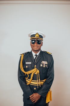 A military officer poses confidently in full dress uniform, exuding professionalism and authority.