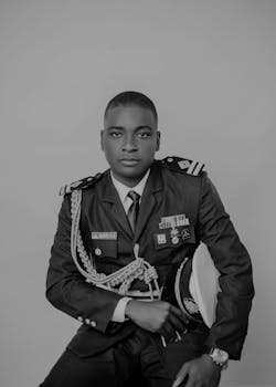 Classic black and white portrait of a young officer in a formal military uniform holding a hat.