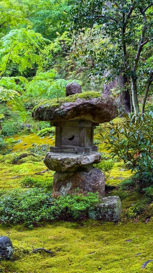 Free Peaceful Japanese stone lantern amidst vibrant green foliage and moss in Kyoto garden. Stock Photo