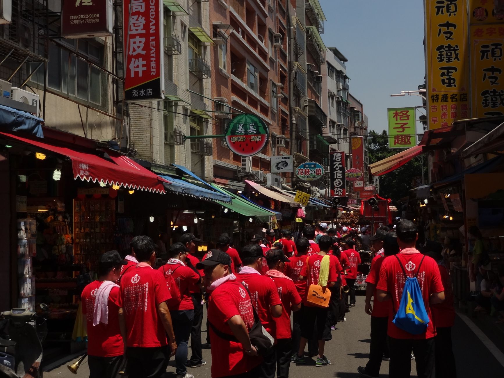 Colorful street market bustling with people in red shirts during a festival.