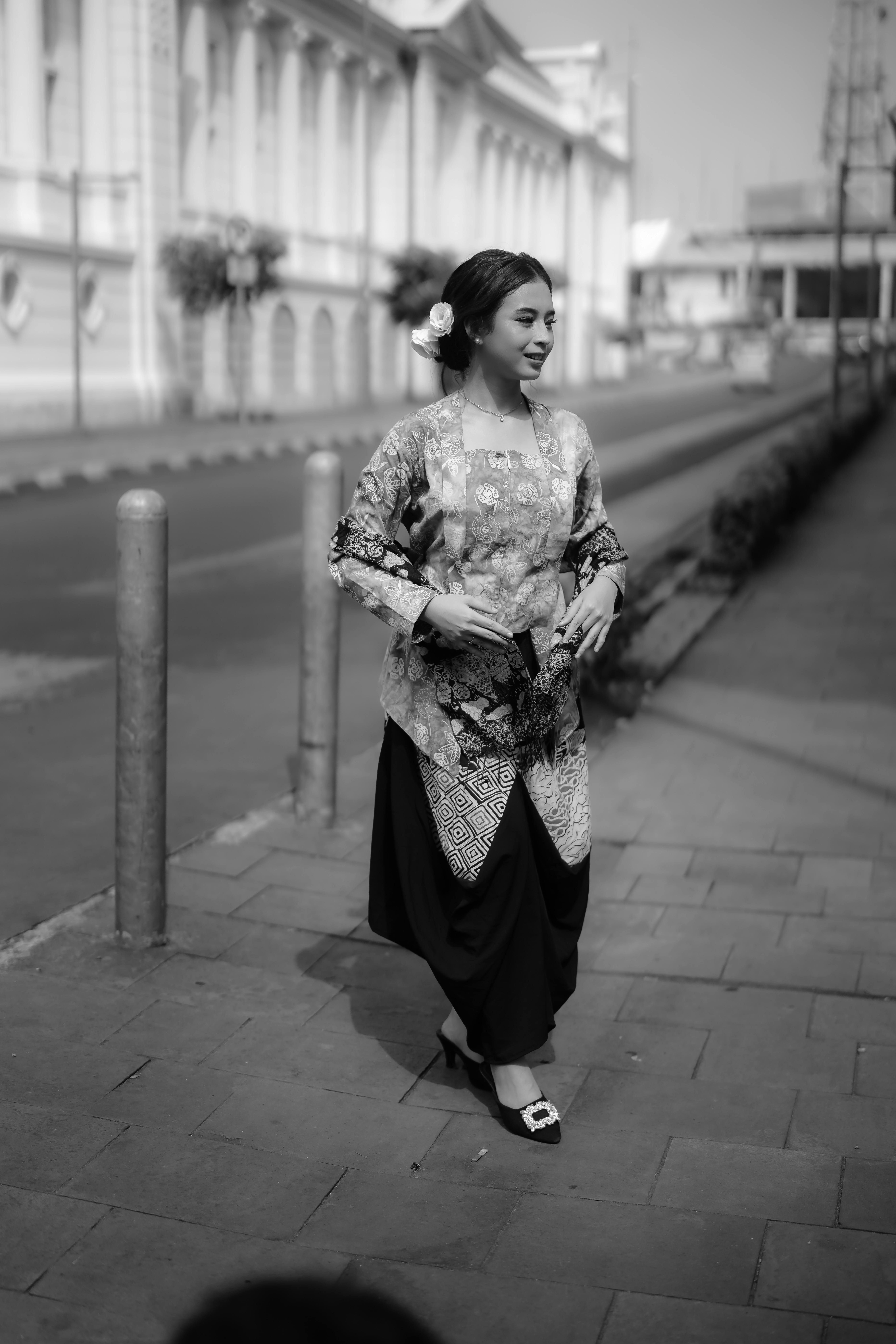 A woman in traditional attire walks down a city street, exuding grace and elegance.