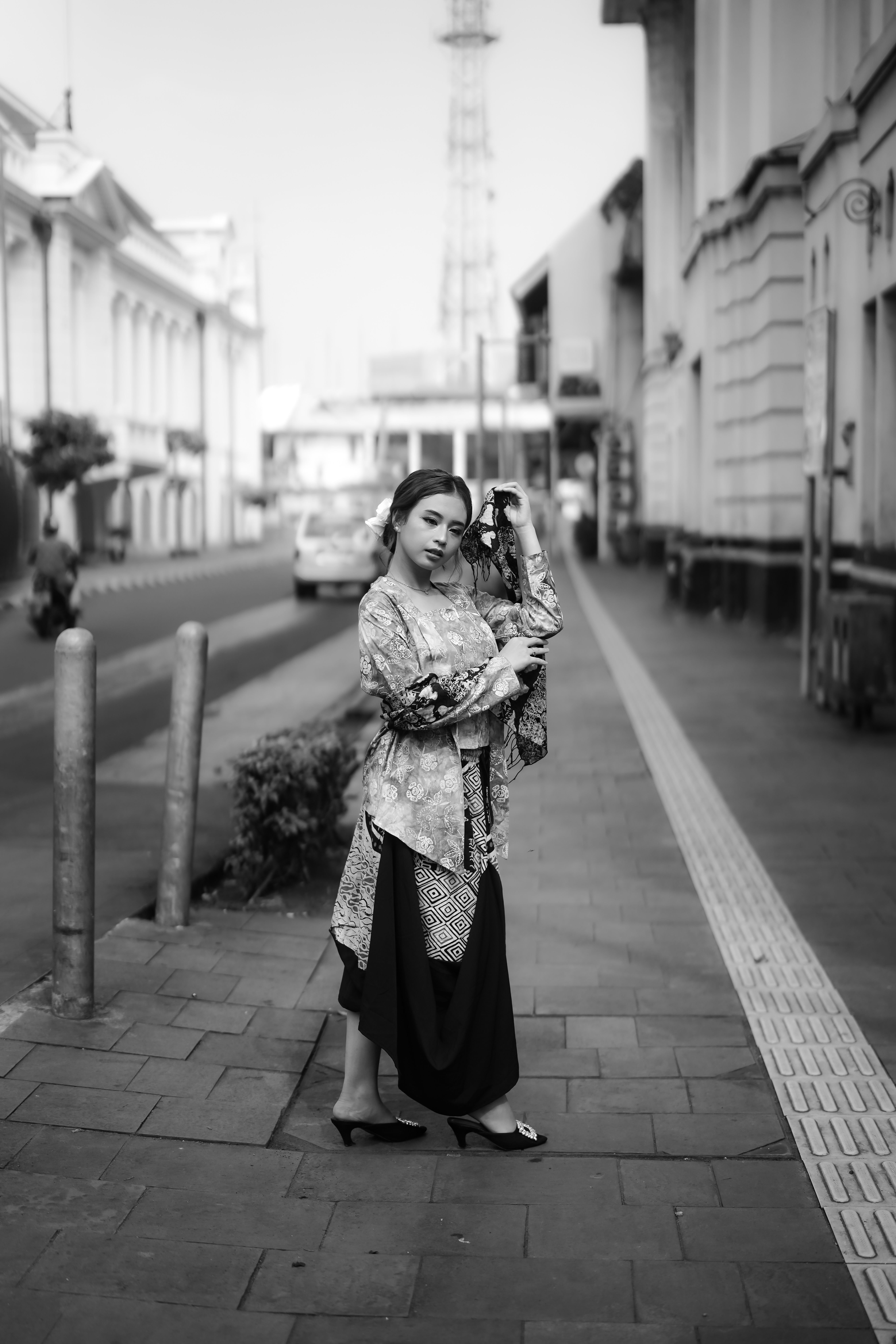 Black and white street portrait of a woman wearing traditional clothing in an urban setting.