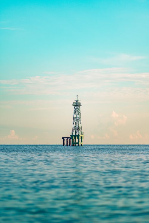 Free A solitary lighthouse tower stands in tranquil waters off South Sulawesi, Indonesia, under a clear sky. Stock Photo