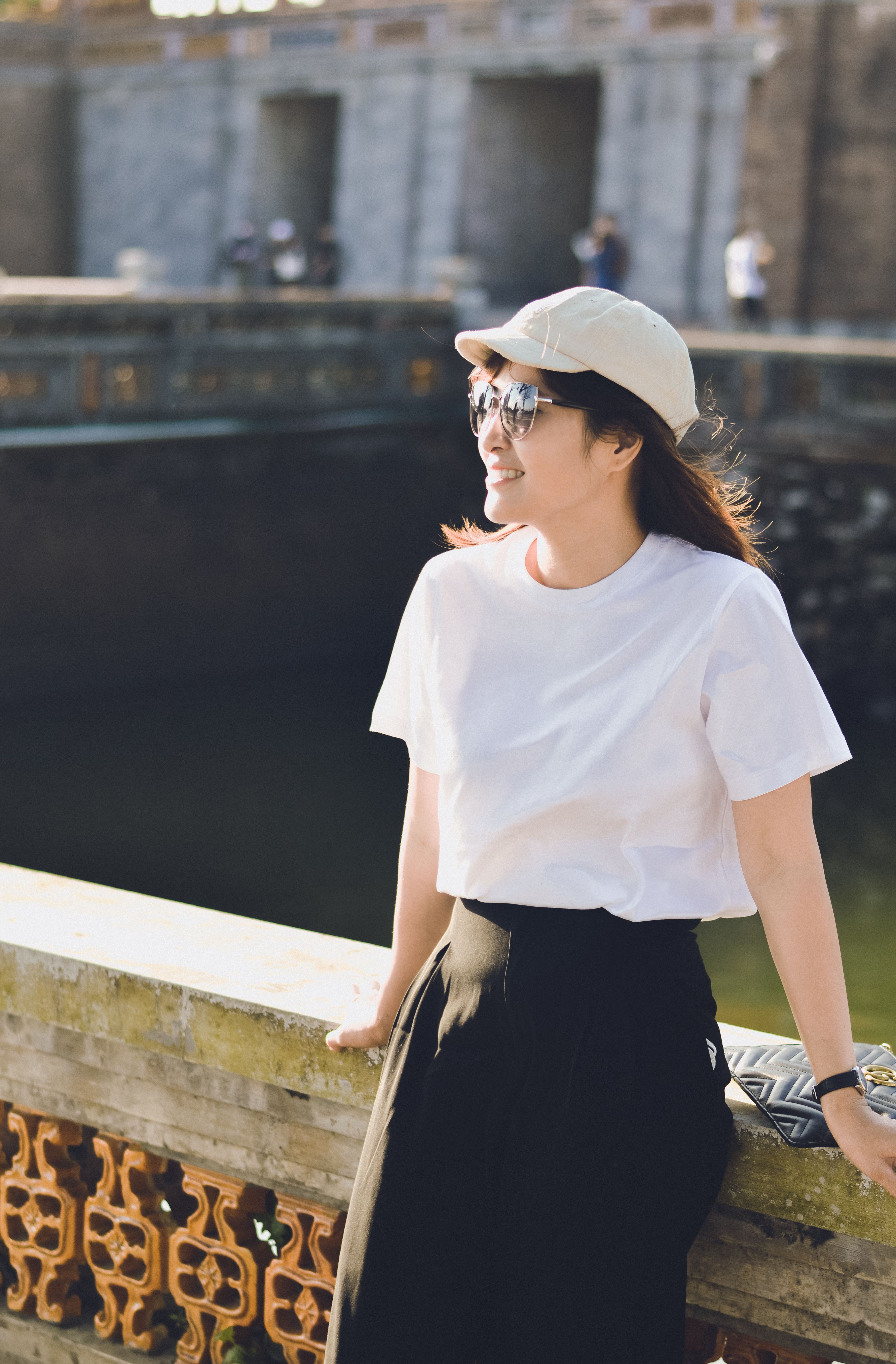 Smiling Woman Posing Outdoors by a Bridge · Free Stock Photo