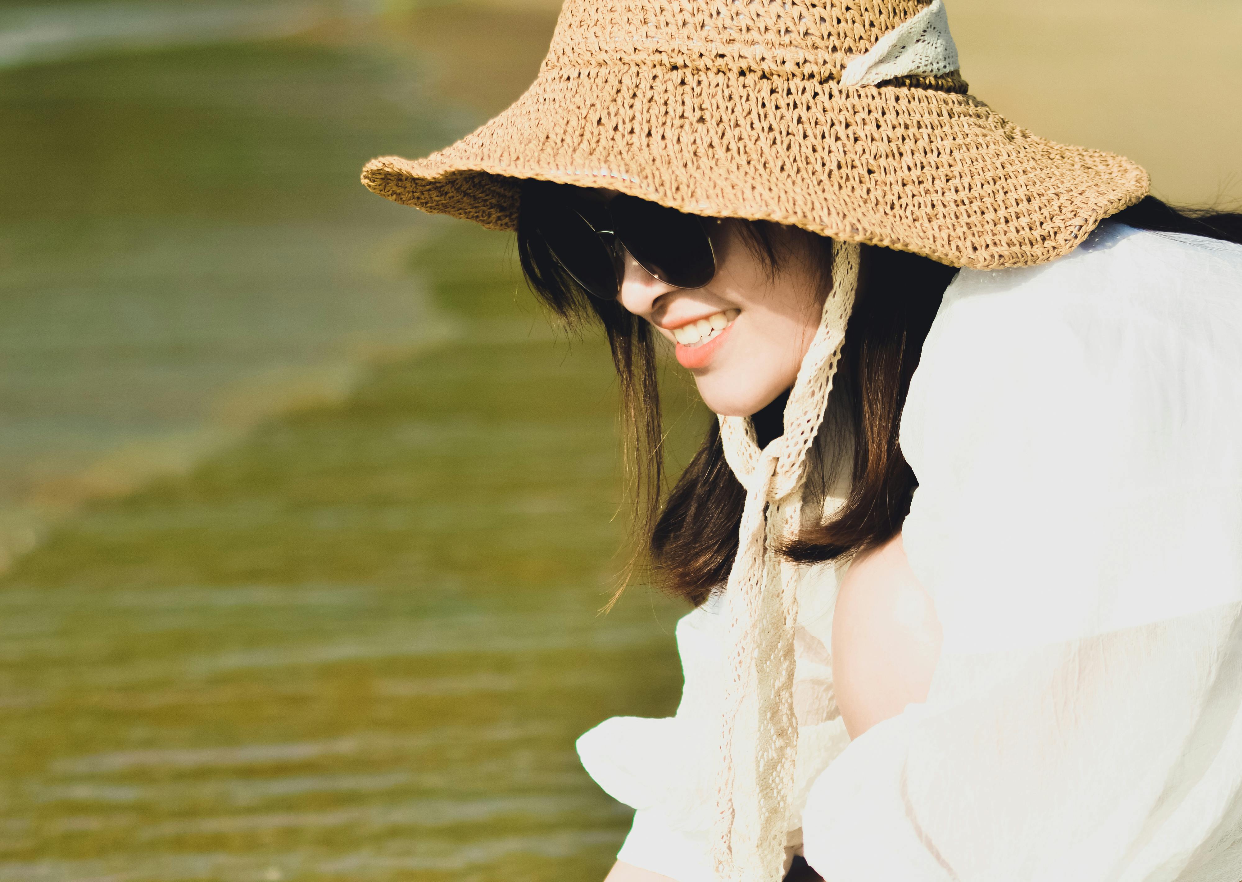 Smiling woman in a sunhat enjoying a sunny day by the seaside.