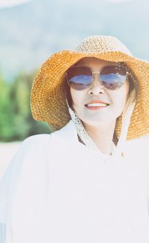 A woman in a straw hat and sunglasses enjoying a sunny day outdoors, showcasing a carefree summer vibe.