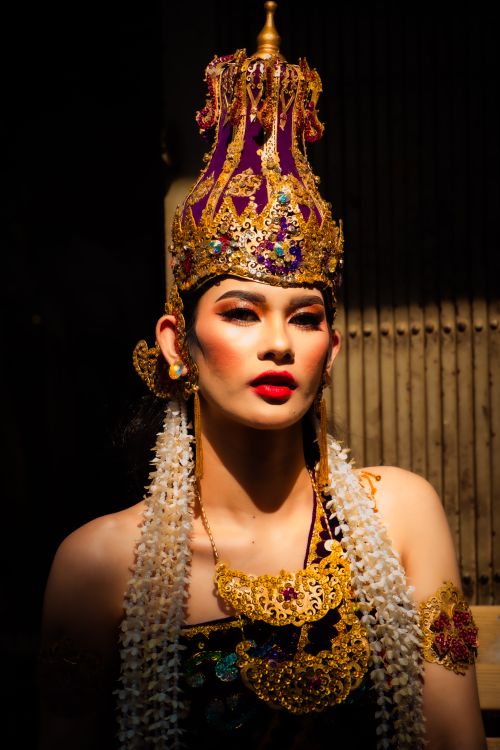Free A striking portrait of a person in a vibrant, ornate traditional Asian costume and headpiece, illuminated by light. Stock Photo