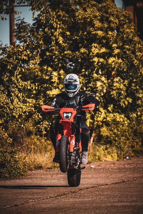 Motorcycle Stunt Rider Performing a Wheelie Outdoors · Free Stock Photo